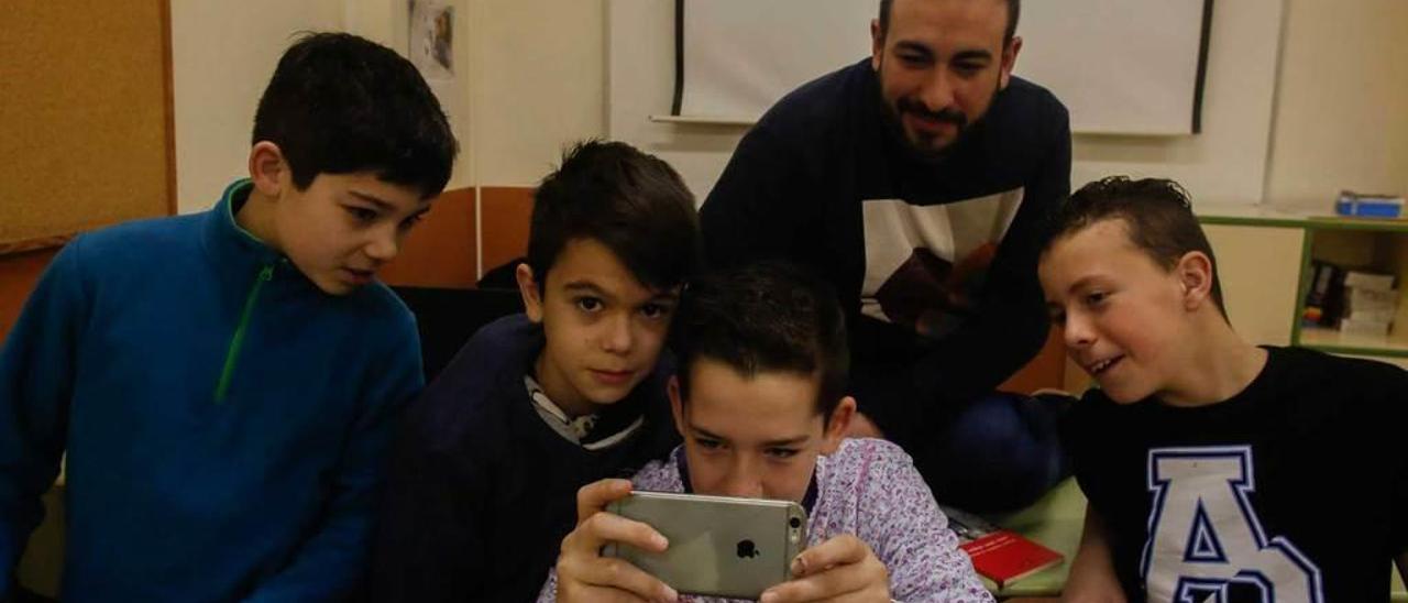 Los alumnos Izan Álvarez, Nel Llope, Iker Corujedo y Marcos González, con el profesor Inaciu Galán, en un aula del Instituto Número 5 y con la proyección del cortometraje a sus espaldas.