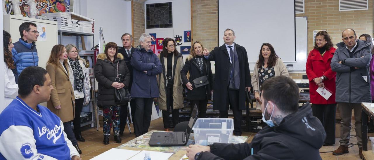 Adolfo Rivas, en el centro, se dirige a uno de los usuarios del centro de normalización a través del arte (CenArte) de la Fundación Vinjoy, durante la visita de un grupo de miembros de la asociación Compromiso Asturias XXI. | Irma Collín
