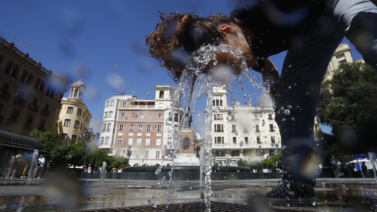 Una turista se refresca en la fuente del patio de los naranjos de la mezquita catedral de Córdoba.