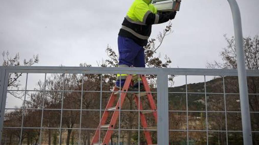 Un operario cambia las bombillas de una farola.