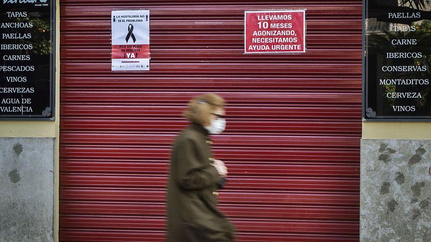Carteles reivindicativos en la persiana de un local hostelero de València cerrado por las restricciones. | GERMÁN CABALLERO