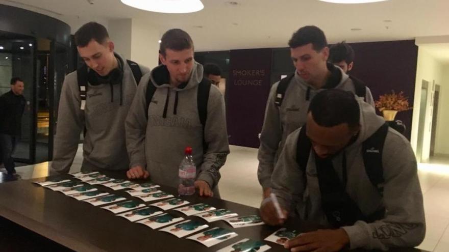 Varios jugadores del Unicaja, a su llegada anoche con un gran retraso al hotel de Berlín, firmando fotos para aficionados.