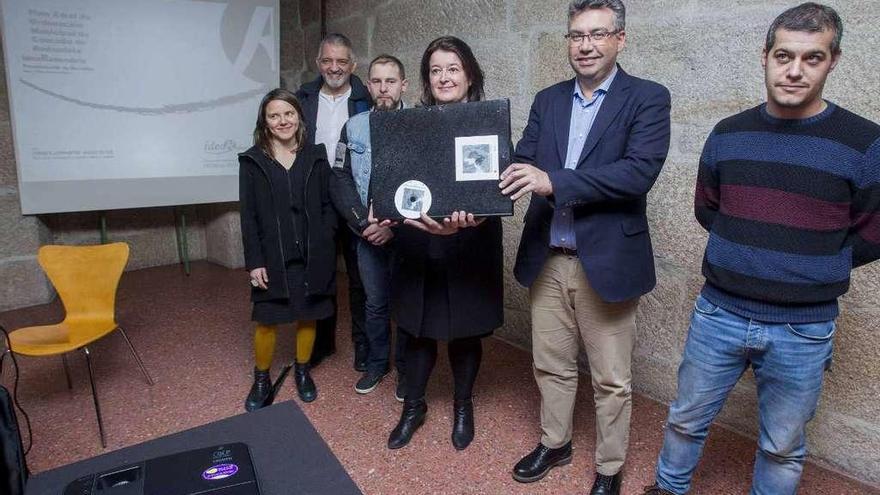 El alcalde Javier Bas y la edil de Urbanismo Mª Carmen Amoedo sostienen el borrador del PXOM, en presencia de miembros del equipo redactor y de la comisión municipal de seguimiento, ayer. // C. Graña