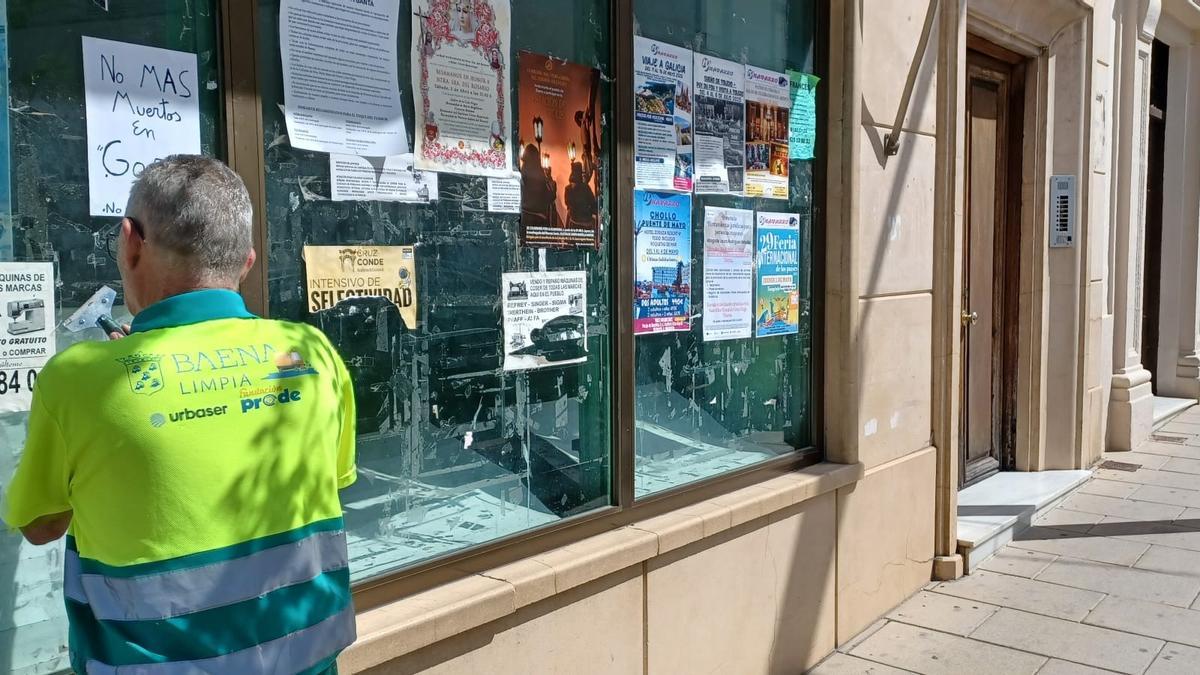 Un empleado de la empresa concesionaria retira carteles de un lugar no autorizado en Baena.