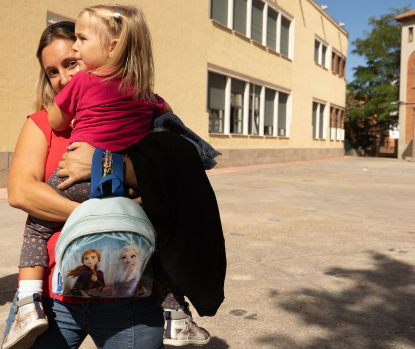 Una madre coge a su hija en brazos tras las clases. | J. L. F.