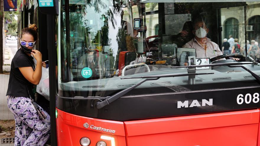 Una joven se coloca la mascarilla para entrar en un bus de TMB, en Barcelona.