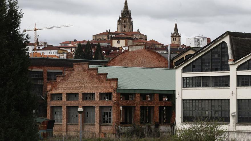 Naves de la fábrica de armas de La Vega en una vista parcial del recinto, con el casco viejo de Oviedo al fondo, coronado por la torre de la  Catedral. | Luisma Murias