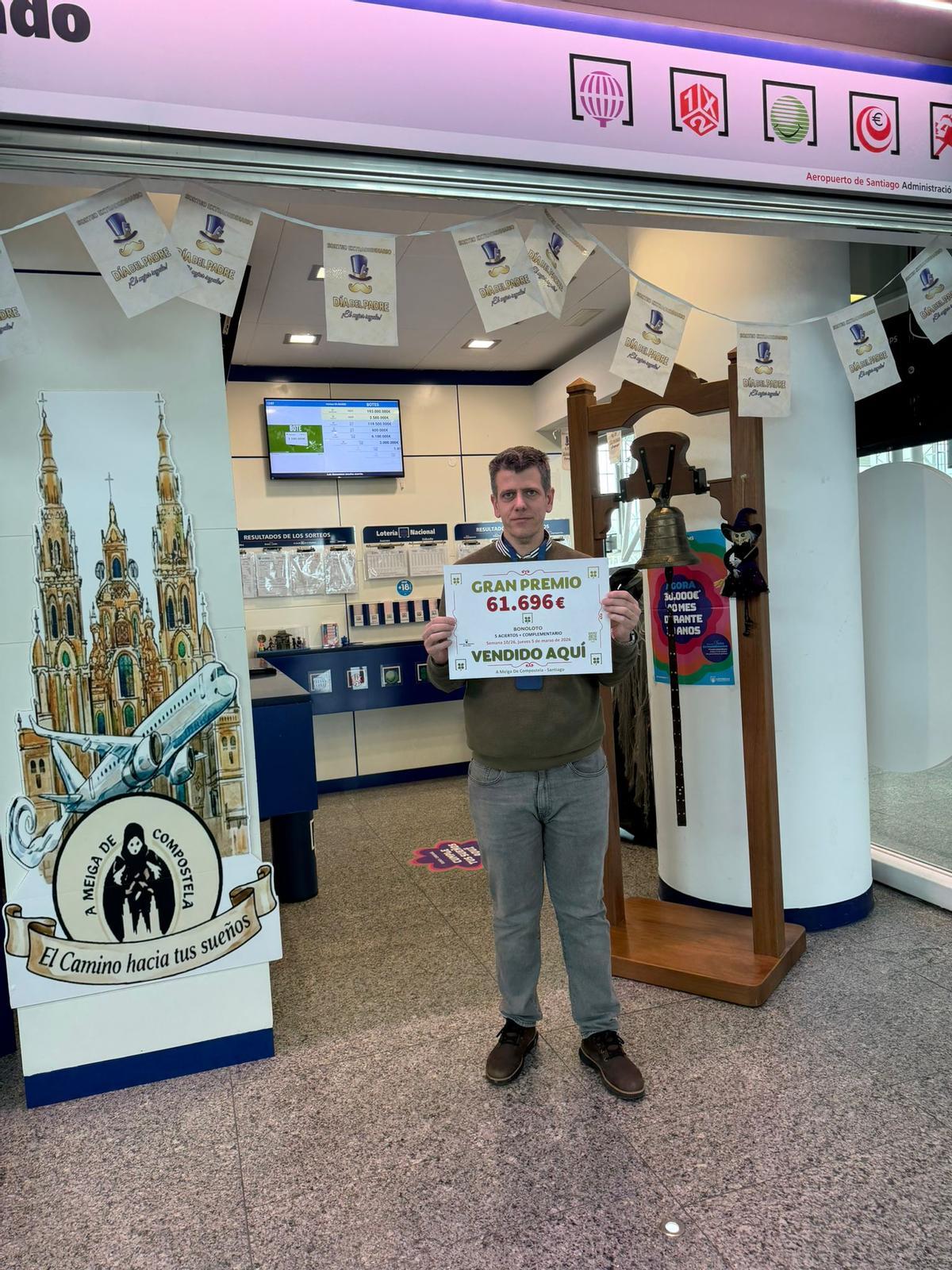 Alberto Lorenzo posa con un cartel con la cuantía del premio en el aeropuerto de Santiago