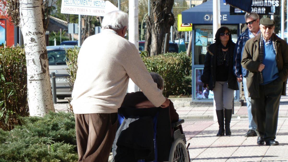 Un hombre pasea a una mujer en silla de ruedas.