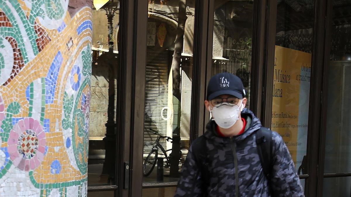 Un joven con mascarilla pasa por delante del Palau de la Música Catalana, el 12 de marzo del 2020