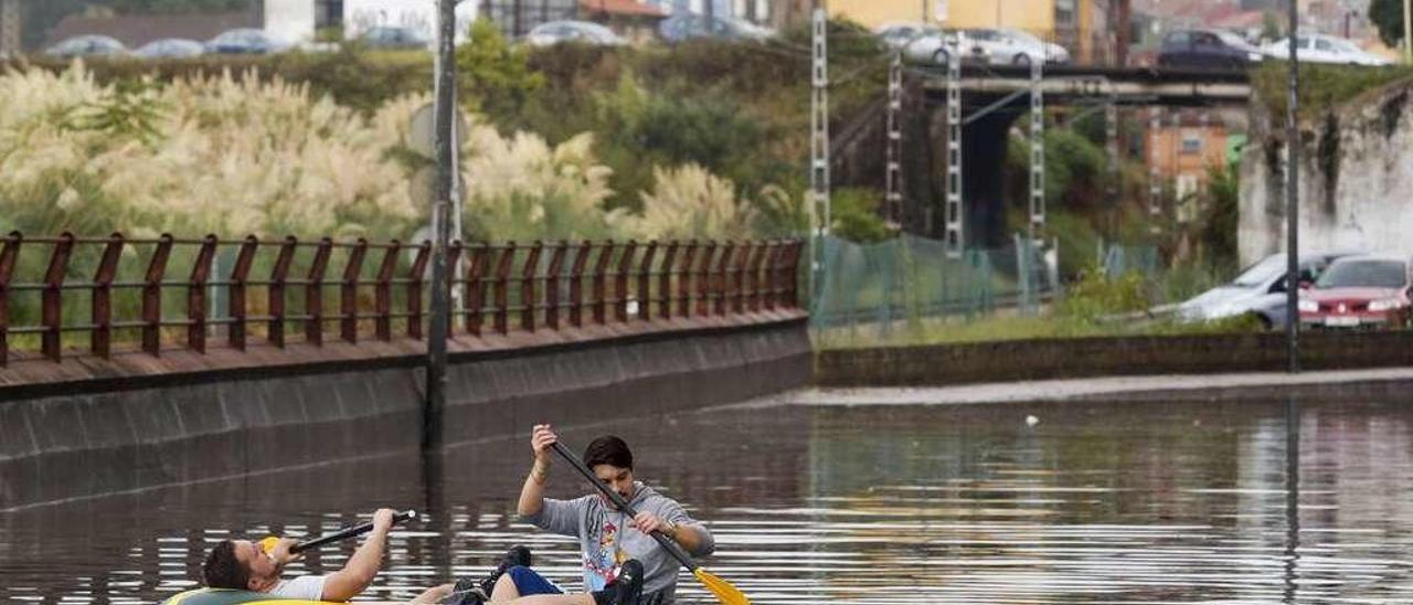 Dos jóvenes, en una lancha en la calle del Muelle, durante las inundaciones de hace un año.