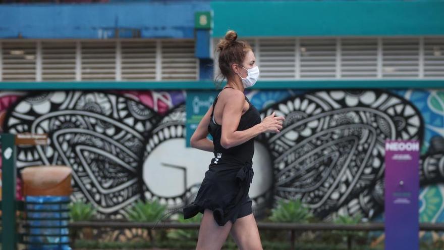 Una chica corres con mascarilla.