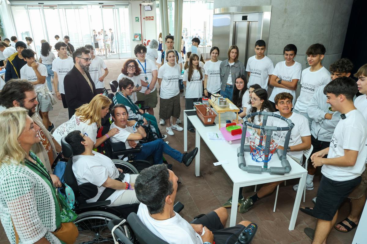 Alumnos del IES Eusebio da Guarda, de A Coruña, explican a un grupo de personas con discapacidad cómo funciona la canasta para piscinas que han creado.