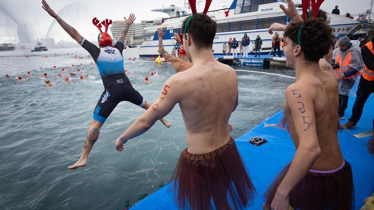 Participantes disfrazados de Papá Noel se lanzan al agua durante la 116.ª edición de la Copa Nadal en el Port Vell de Barcelona