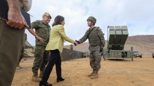La ministra Margarita Robles saluda a un soldado de Canarias con la batería antimisiles al fondo.