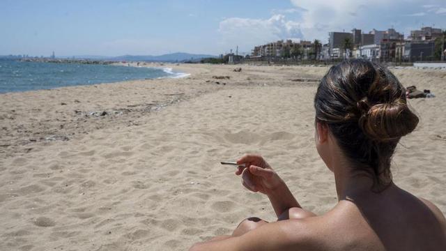 Una jove sosté un cigarret a la platja del Pla de l’Ós a Premià de Mar
