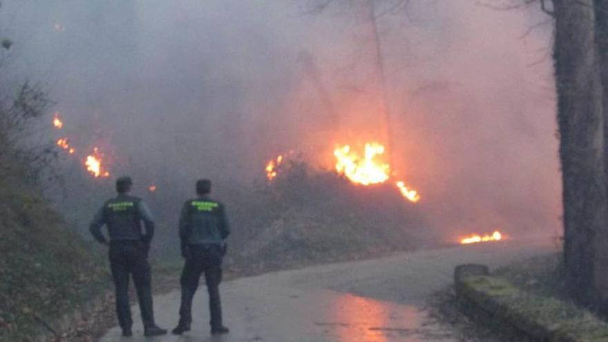 Dos guardias, en la carretera llanisca de Llamigu, afectada por un incendio.