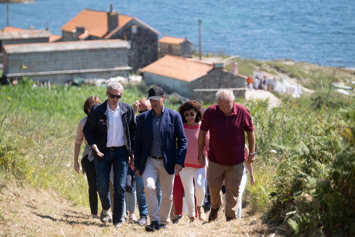 El presidente de la Xunta de Galicia, Alfonso Rueda, conversa con el alcalde de Bueu, Félix Juncal, y el director del parque nacional, José Antonio Fernández, en una visita este verano.
