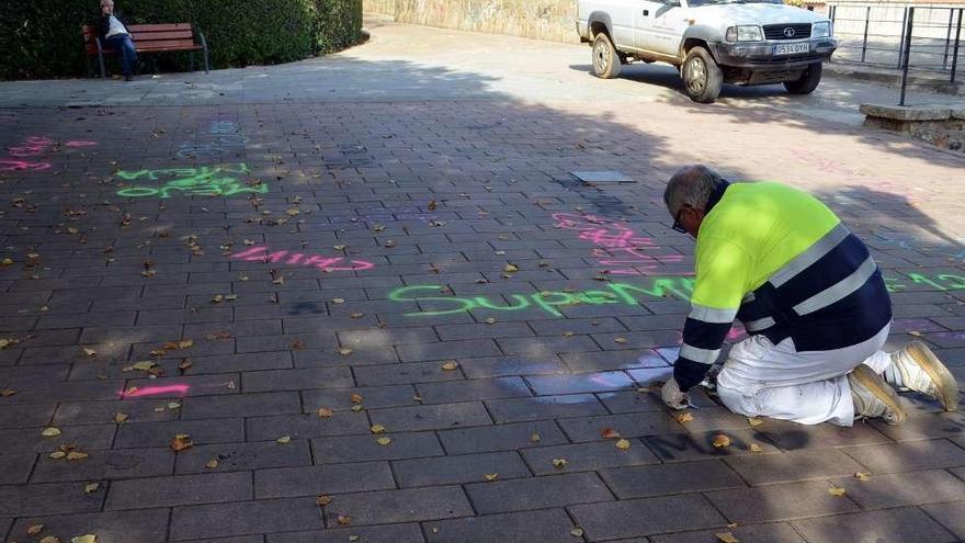 Un operario municipal limpia las pintadas del suelo.