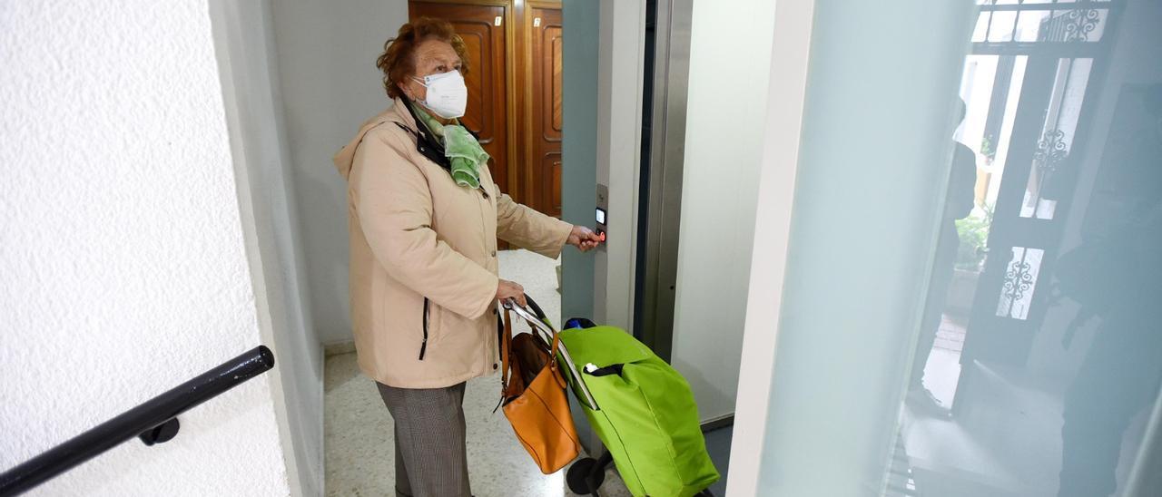 Una mujer entra en un ascensor en un bloque de pisos de Córdoba con su mascarilla puesta.