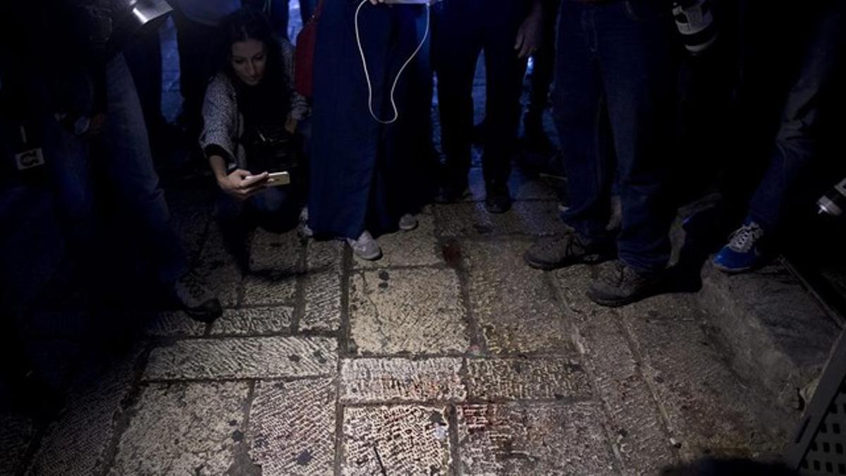 Unos curiosos toman fotos de una mancha de sangre en el lugar del apuñalamiento de ese miércoles en Jerusalén.