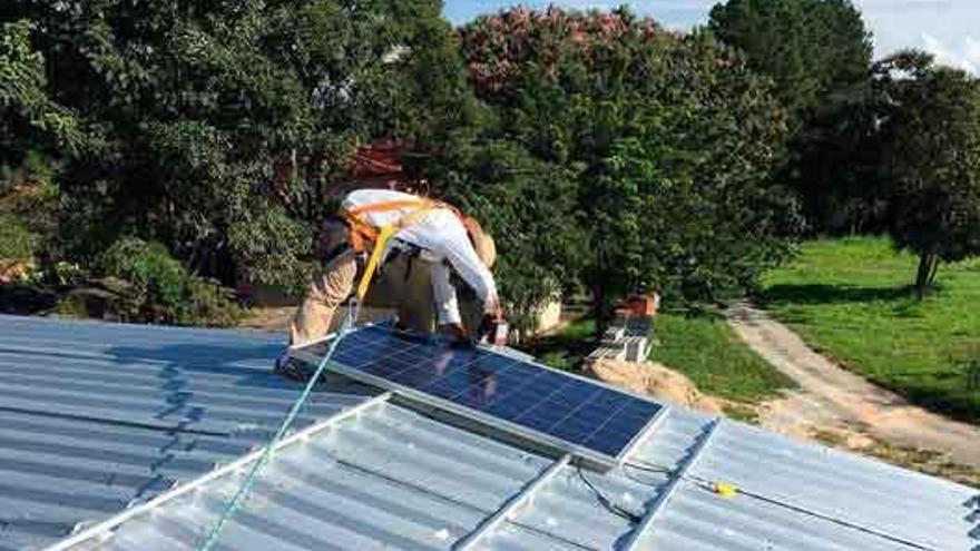 Un operario instala una placa solar en un tejado.
