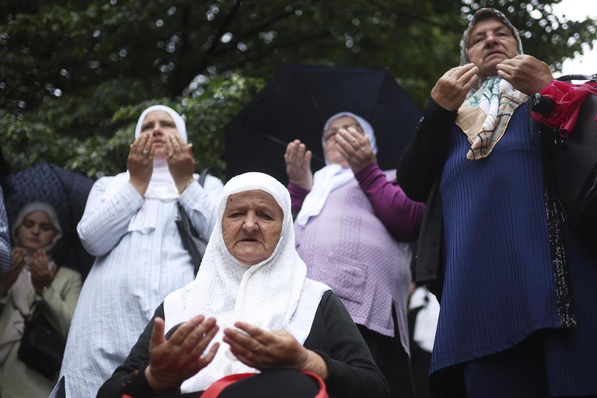 Mujeres bosnias rezan ante los restos de víctimas de la masacre de Srebrenica de 1995 y que serán enterrados este viernes en el Centro Memorial de Potocari, en Visoko.
