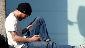 Un chico joven consulta su teléfono móvil.