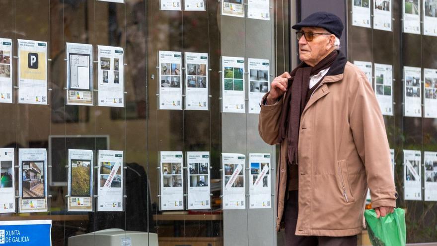 Un hombre pasa por delante de una inmobiliaria, con los anuncios en el escaparate. | Germán Barreiros/Roller Agencia