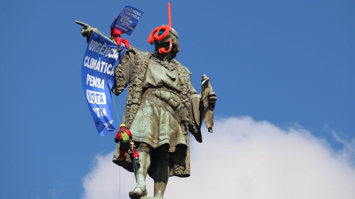 Dos activistas de Greenpeace colocan unas gafas de buzo a la estatua de Colón