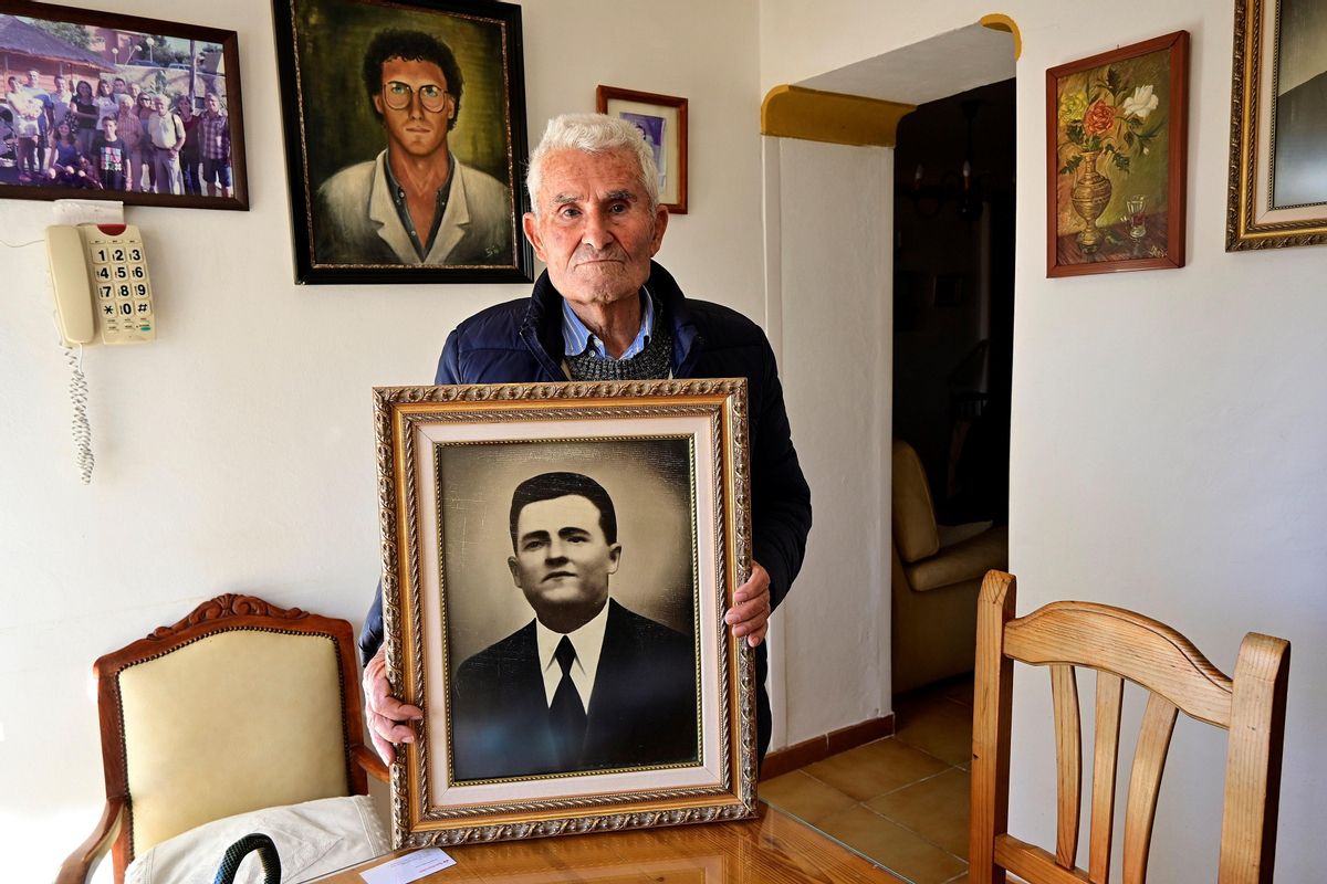 Pepe Alarcón García, de 90 años, fotografiado con el retrato de su padre en su casa en Vélez-Málaga durante una entrevista con la Agencia EFE