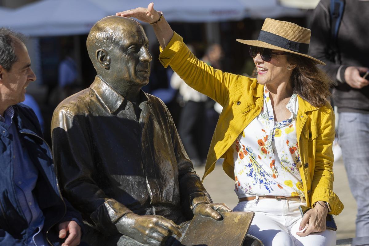 Unos turistas se sientan junto a la estatua de Pablo Ruiz Picasso de la Plaza de la Merced