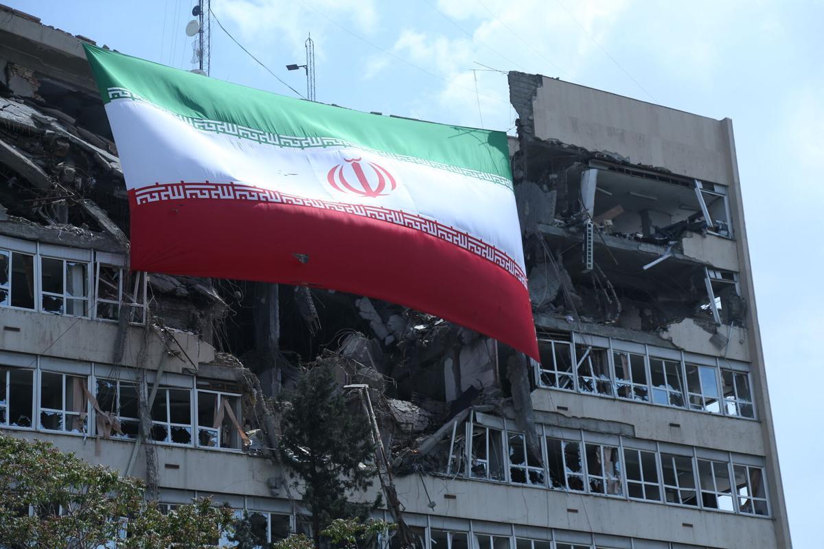Una bandera de Irán sobre un edificio de Teherán dañado por los bombardeos.