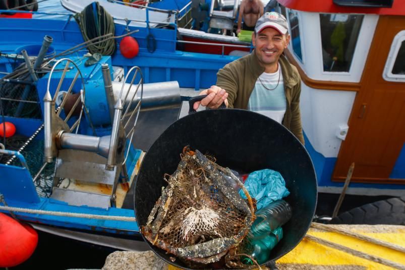 Un marinero muestra basura recién pescada.