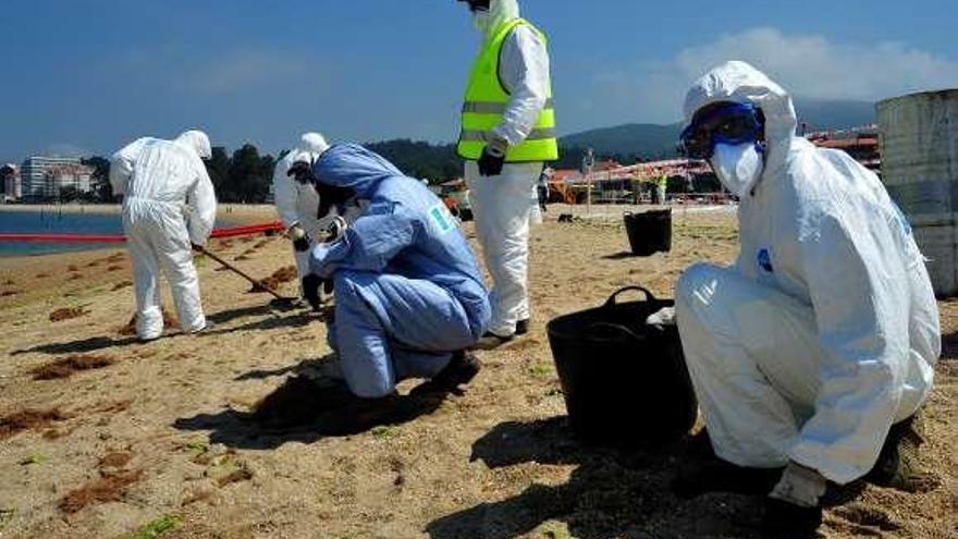 Un grupo de operarios limpian la playa a mano.