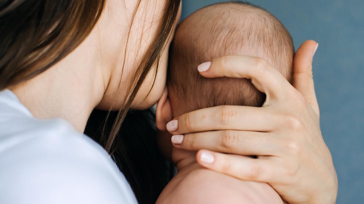 Una mujer besa a su hijo recién nacido.