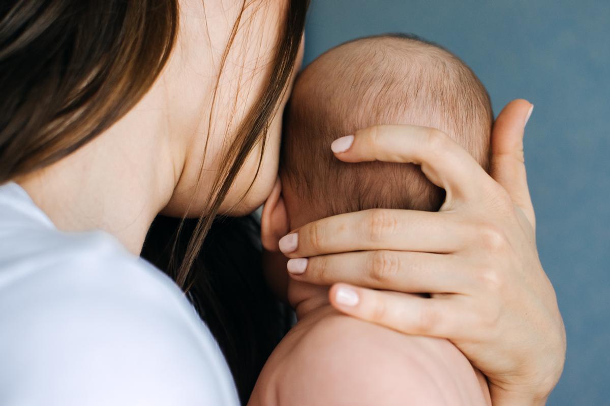 Una mujer besa a su hijo recién nacido.