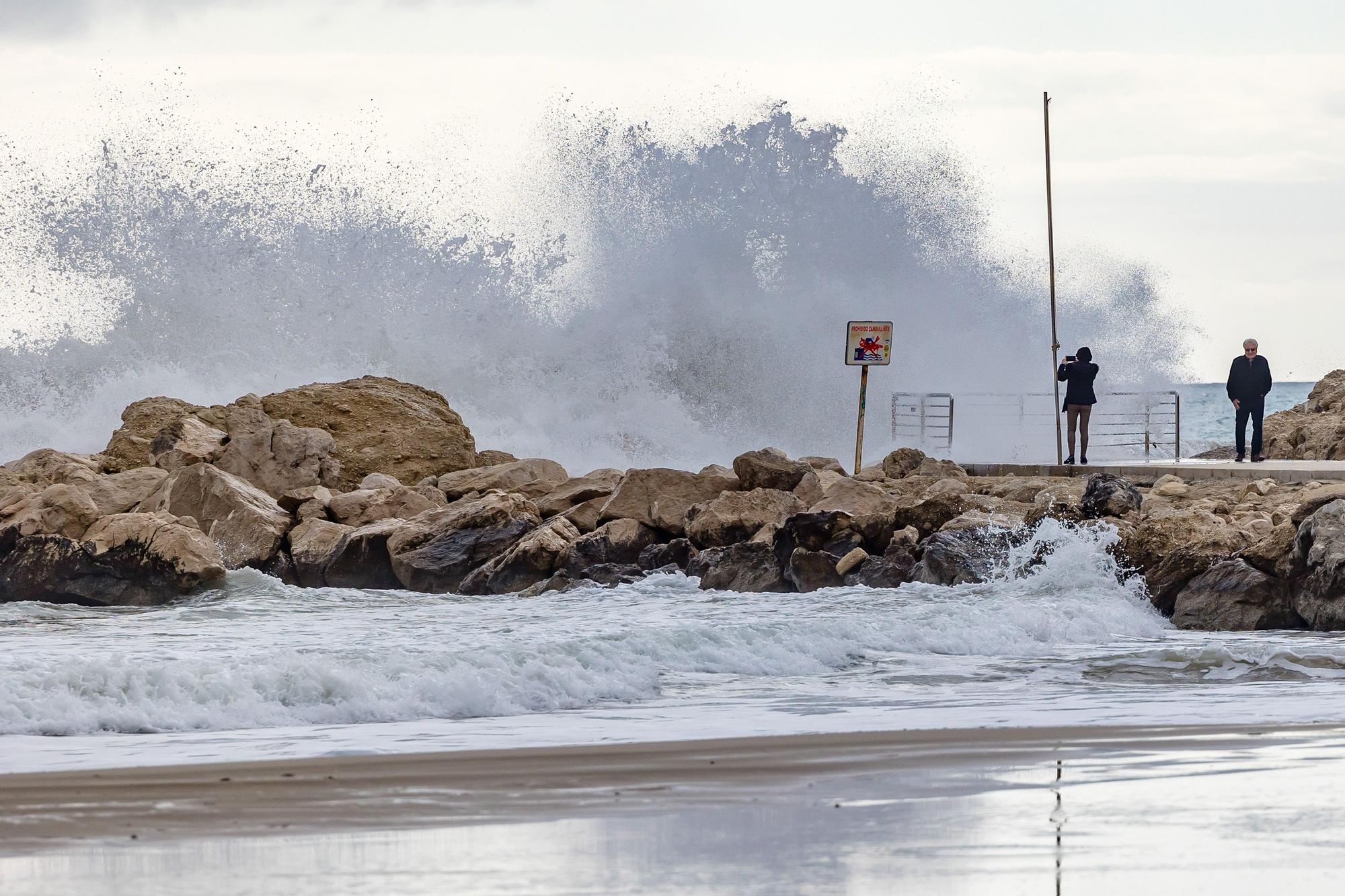 Turistas y paseantes observan el temporal de mar en la Cala de Finestrat