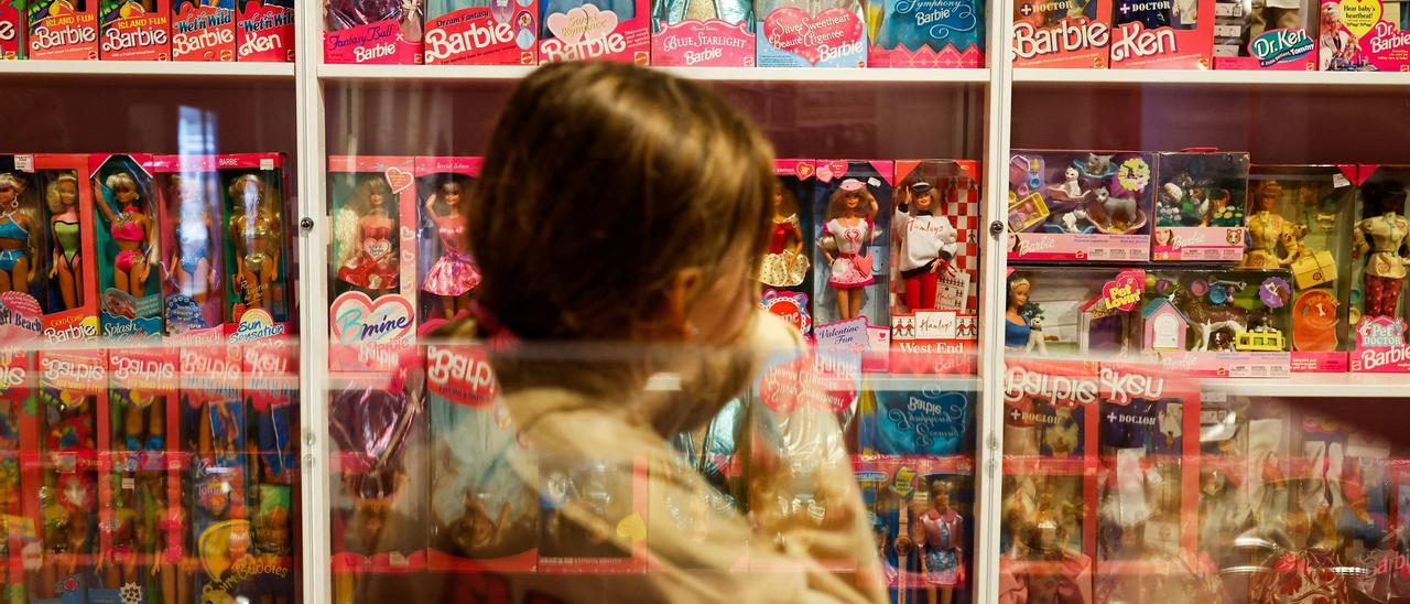 Una niña mira las Barbie de un escaparate.