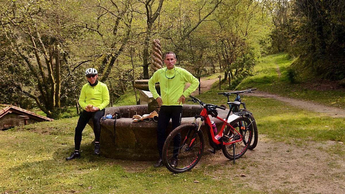 Dos ciclistas comen algo en el conjunto escultórico de la Aldea Labrega, ayer.   | // NOÉ PARGA