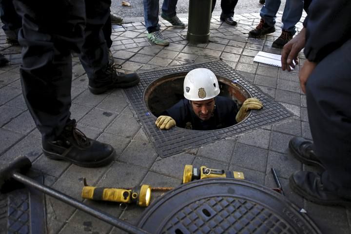 Policemen check a drain outside the Santiago Bernabeu stadium before the 'Clasico' soccer match between Real Madrid and Barcelona in Madrid, Spain