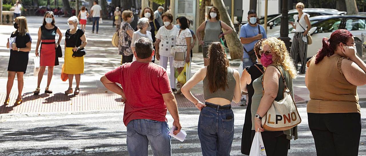 Vecinos de Xàtiva aguardan a cruzar una calle, en una fotografía de hace unos días | PERALES IBORRA