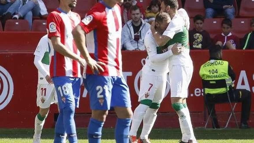 Geraldes y Traver, abatidos, con Nino al fondo siendo felicitado por sus compañeros tras marcar ayer en El Molinón.