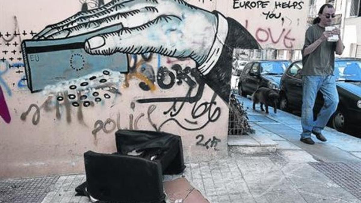 Un hombre pasa ante un grafiti de denuncia en la ciudad de Atenas, este lunes.