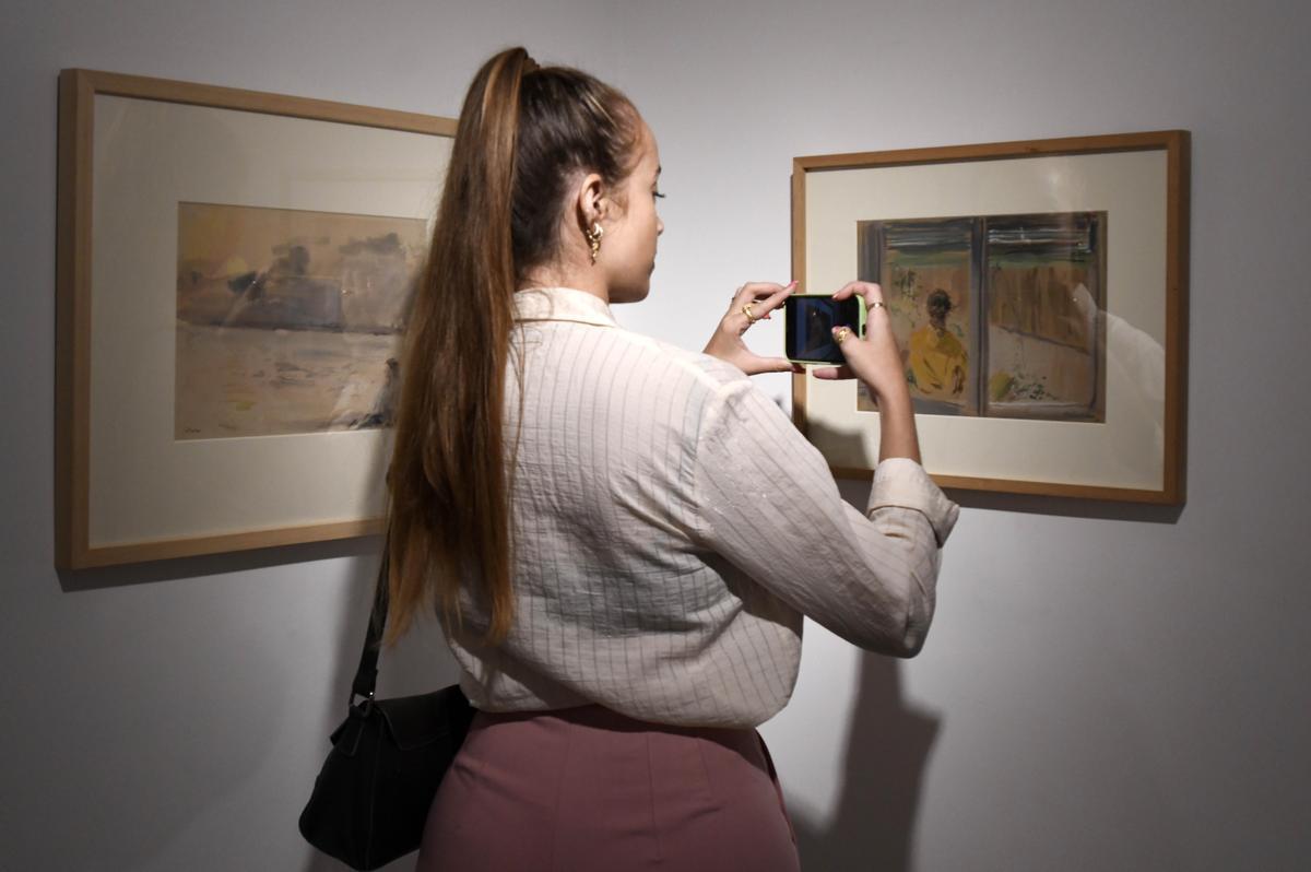 Una joven fotografía una de las acuarelas de Serna.