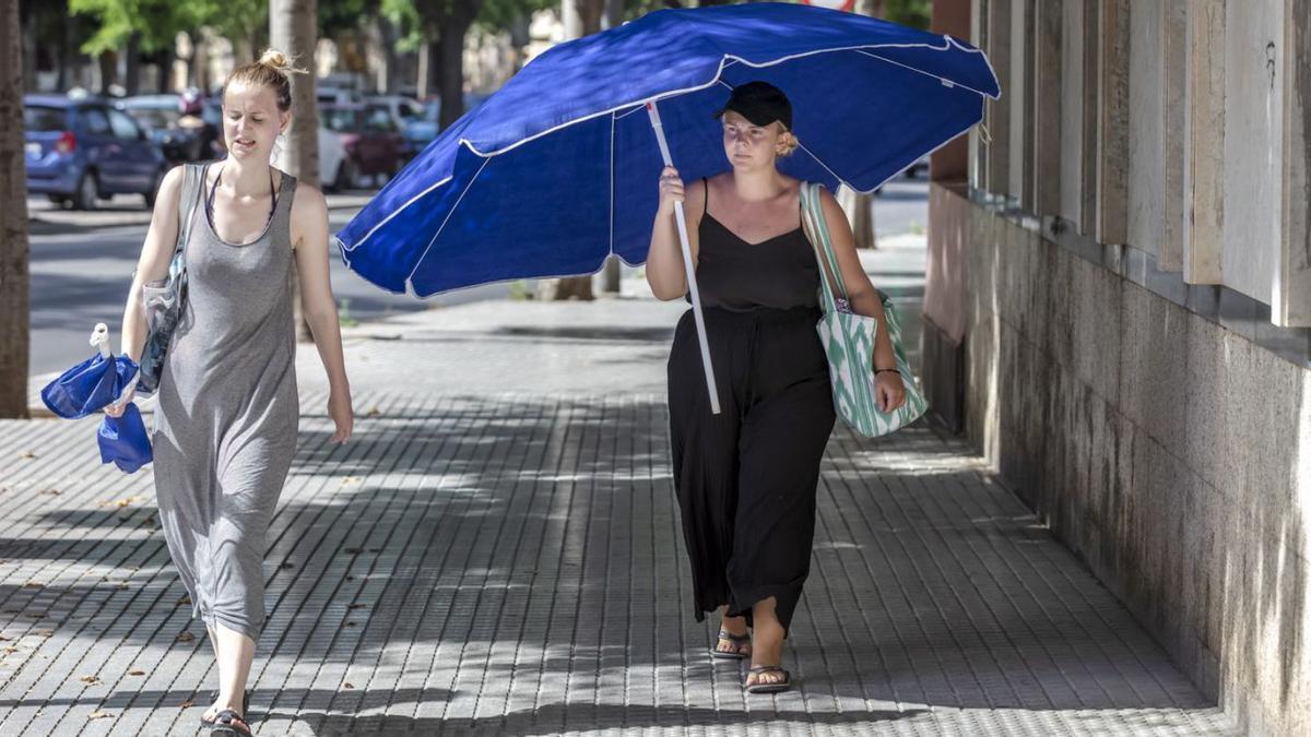 Una mujer se protege del sol con una sombrilla mientras pasea por el centro de Palma. | B.RAMON