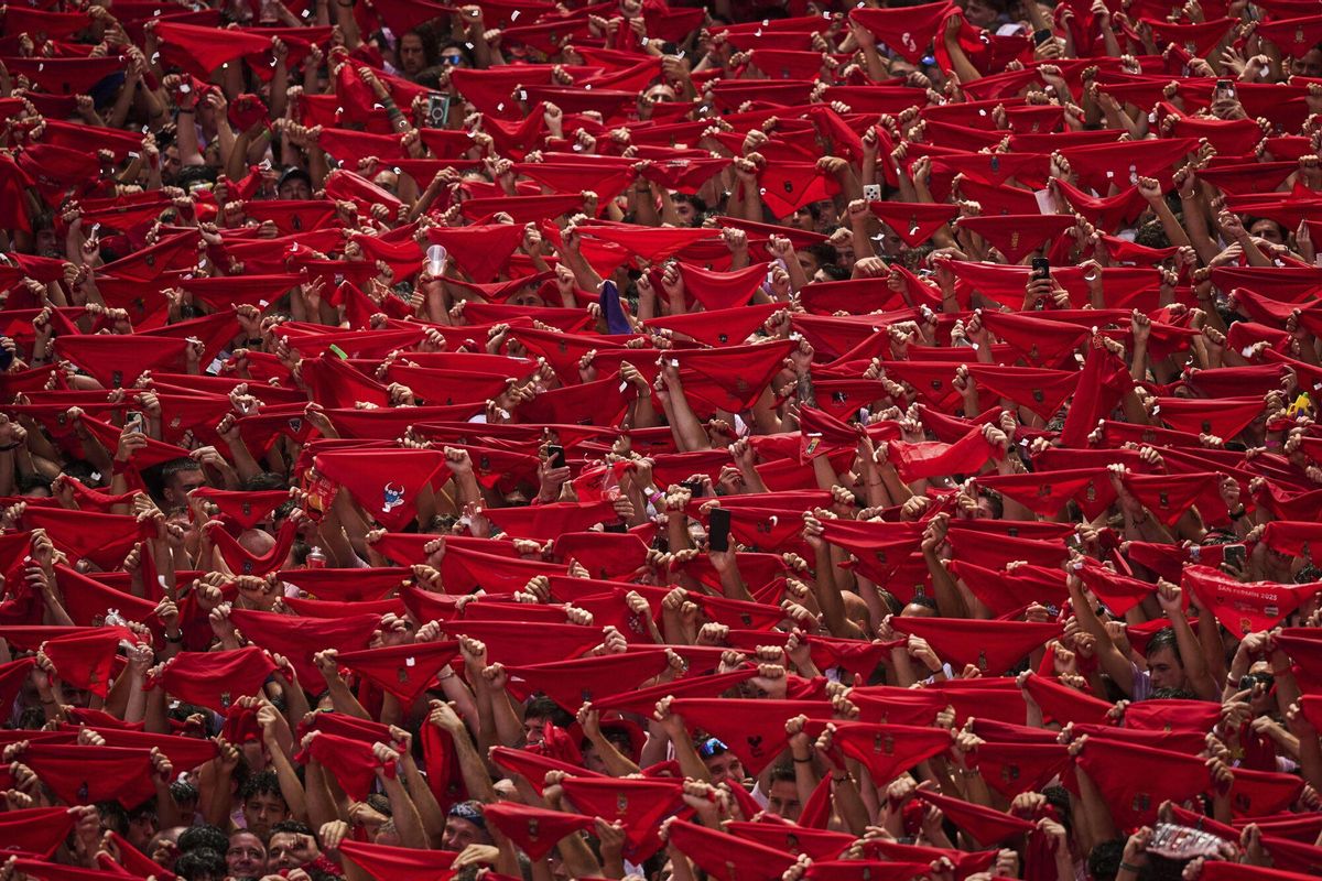 Revelers hold up red neckties as they pack the main square during the start of nine days of uninterrupted partying in Pamplonas famed running-of-the-bulls festival in Pamplona, Spain, Sunday, July 6, 2025. (AP Photo/Miguel Oses). EDITORIAL USE ONLY/ONLY ITALY AND SPAIN