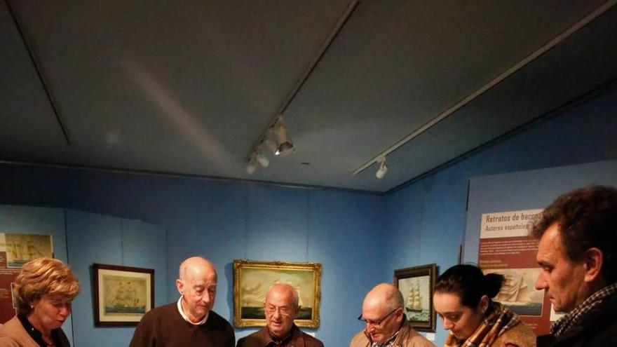 José Ramón García desvela los secretos de la exposición de pinturas de barcos a los primeros visitantes de la muestra, entre ellos el alcalde de Gozón, Jorge Suárez, a la derecha.