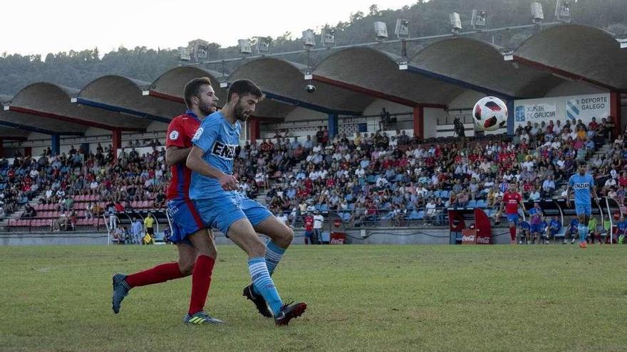 El delantero de la UD Ourense Adrián Vaz es frenado por un defensa del Alondras, ayer en O Couto. // Enzo Sarmiento