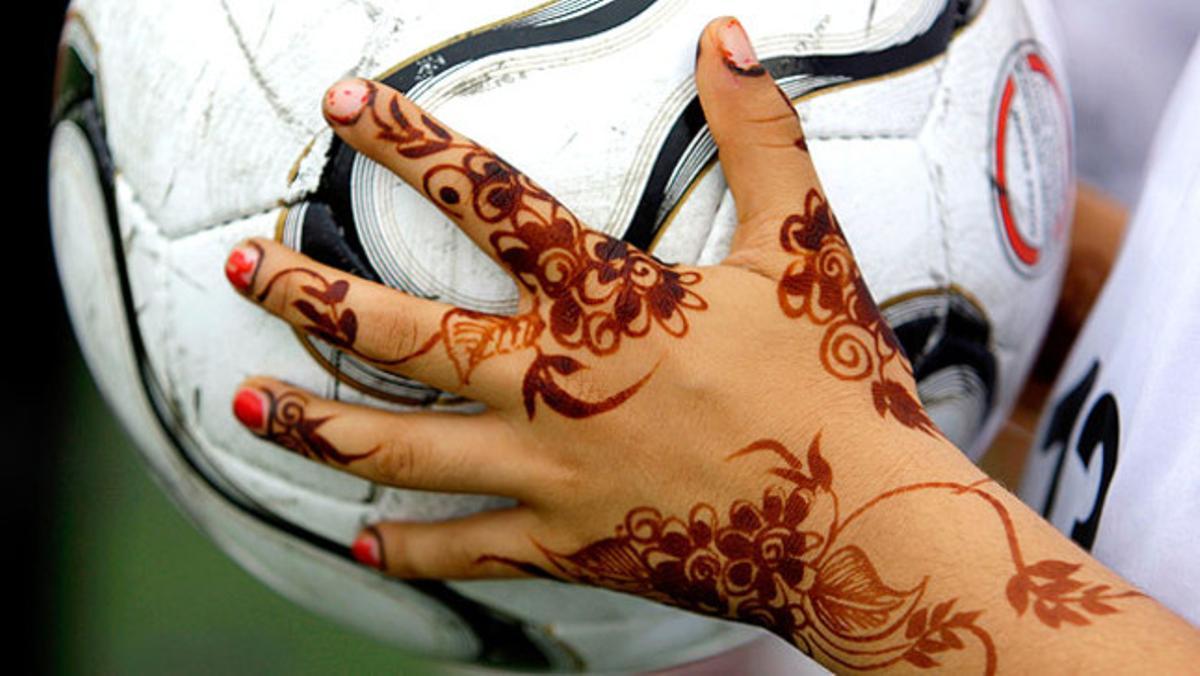 Una jugadora de futbol dels Emirats Àrabs mostra dissenys de henna a les mans abans d’un llançament lateral.